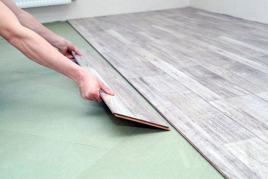 A worker laying laminate floorboards in a residential space, representing a flooring service in Jacksonville, FL.